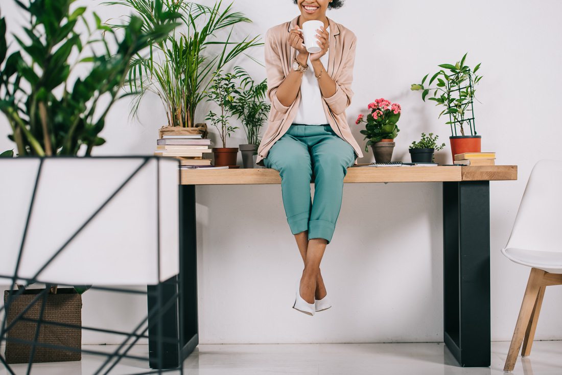 Woman sitting on desk with office plants