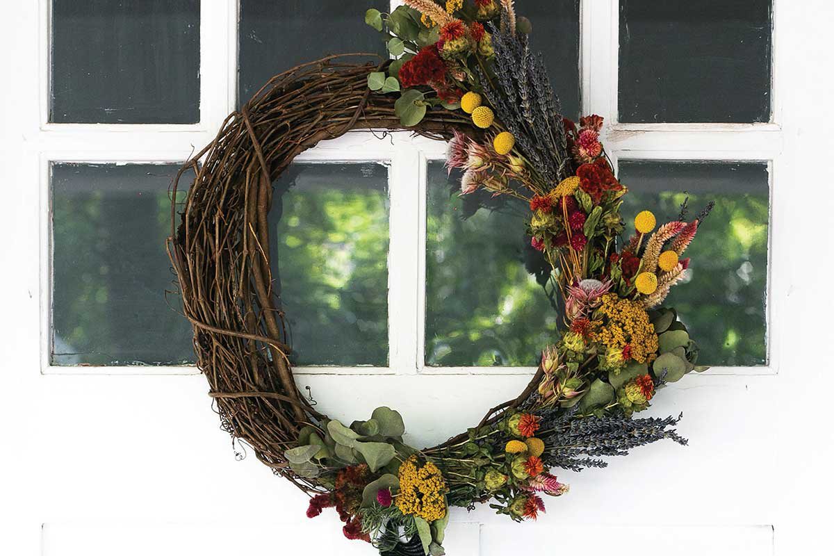 fall wreath hung on a white windowed front door